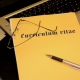 Foto: gelbe Lebenslauf-Mappe mit Brille und Kugelschreiber auf eine Tastatur