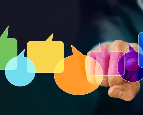 Fotomontage: Finger hinter unterschiedlich farbigen Sprechblasen